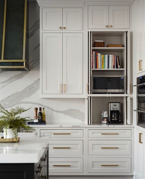 This is a great example of the implementation of many trends. You’ll notice the neutral color palette with interesting hardware, the extension of both the counter stone slab and cabinets all the way up to the ceiling, an accent kitchen island, an appliance cabinet with pocket doors, and flush cabinet and drawer panels.